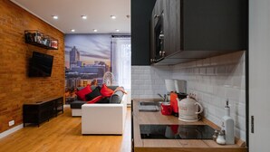 Una sala de estar moderna con un mural de la ciudad, un sofá con cojines rojos, un televisor de pantalla plana y una mesa de centro de madera.
