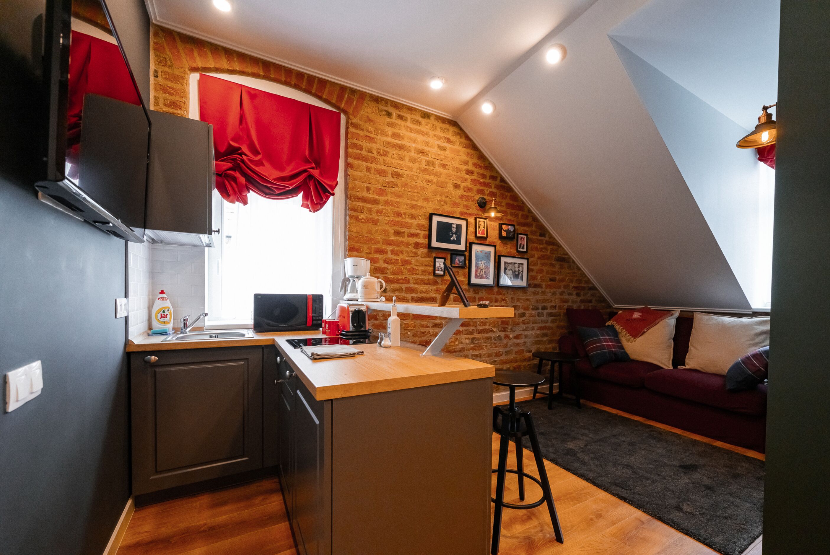 A compact kitchen with a wooden countertop, a built-in oven, and a red curtain.