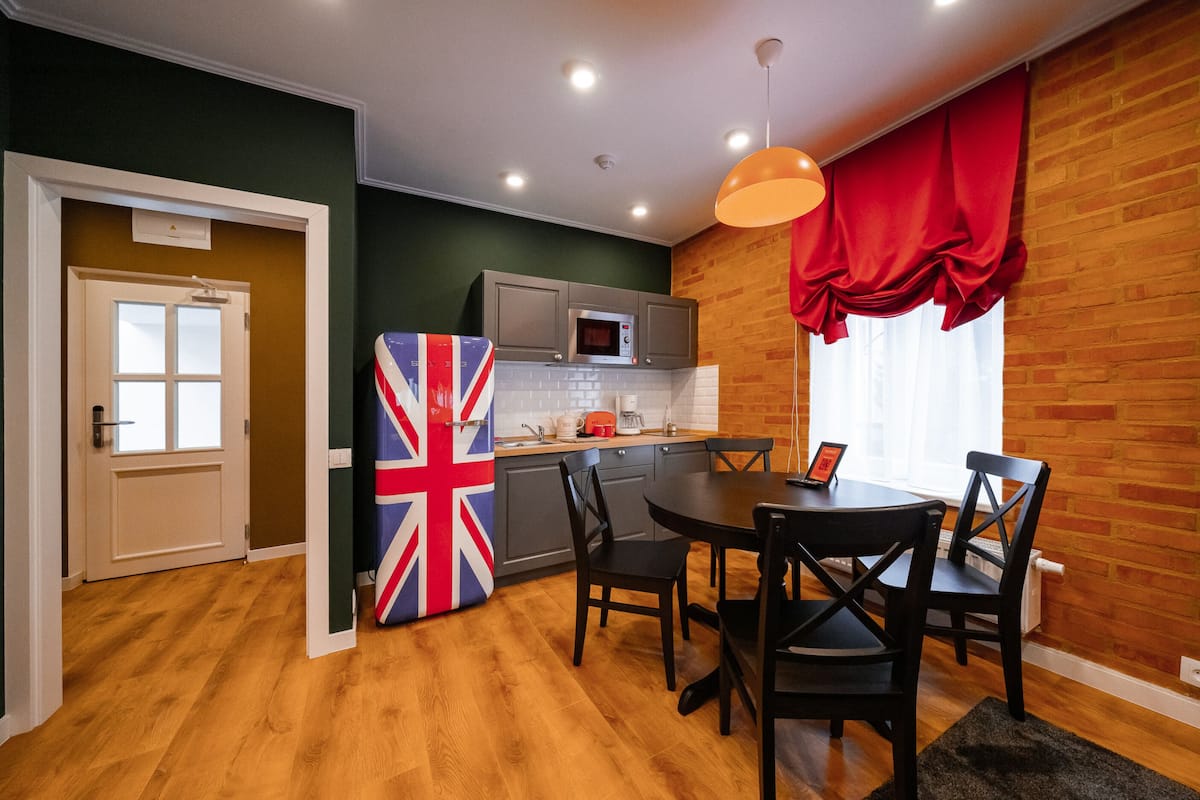 Cocina compacta con microondas, armarios y comedor con sillas y una mesa.