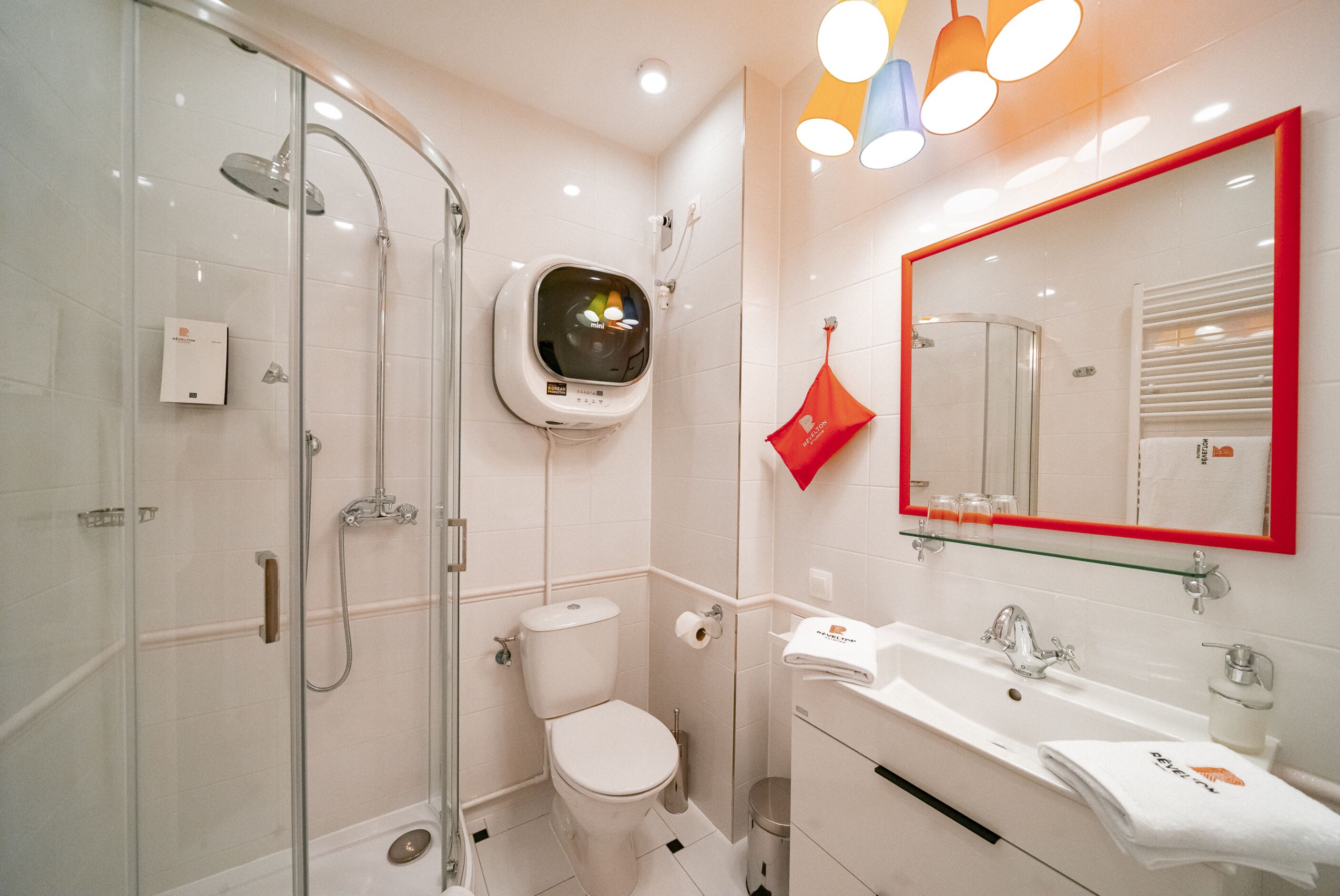 Une salle de bain moderne avec une douche à parois de verre, des toilettes, un lavabo avec un miroir et un porte-serviettes.