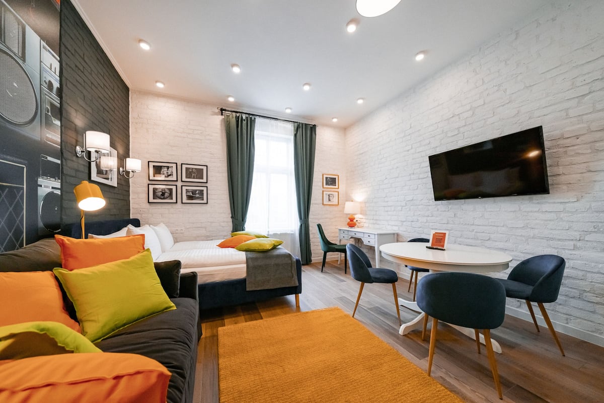 Una habitación de hotel moderna con una cama, un escritorio, una silla, un televisor y un televisor montado en la pared.