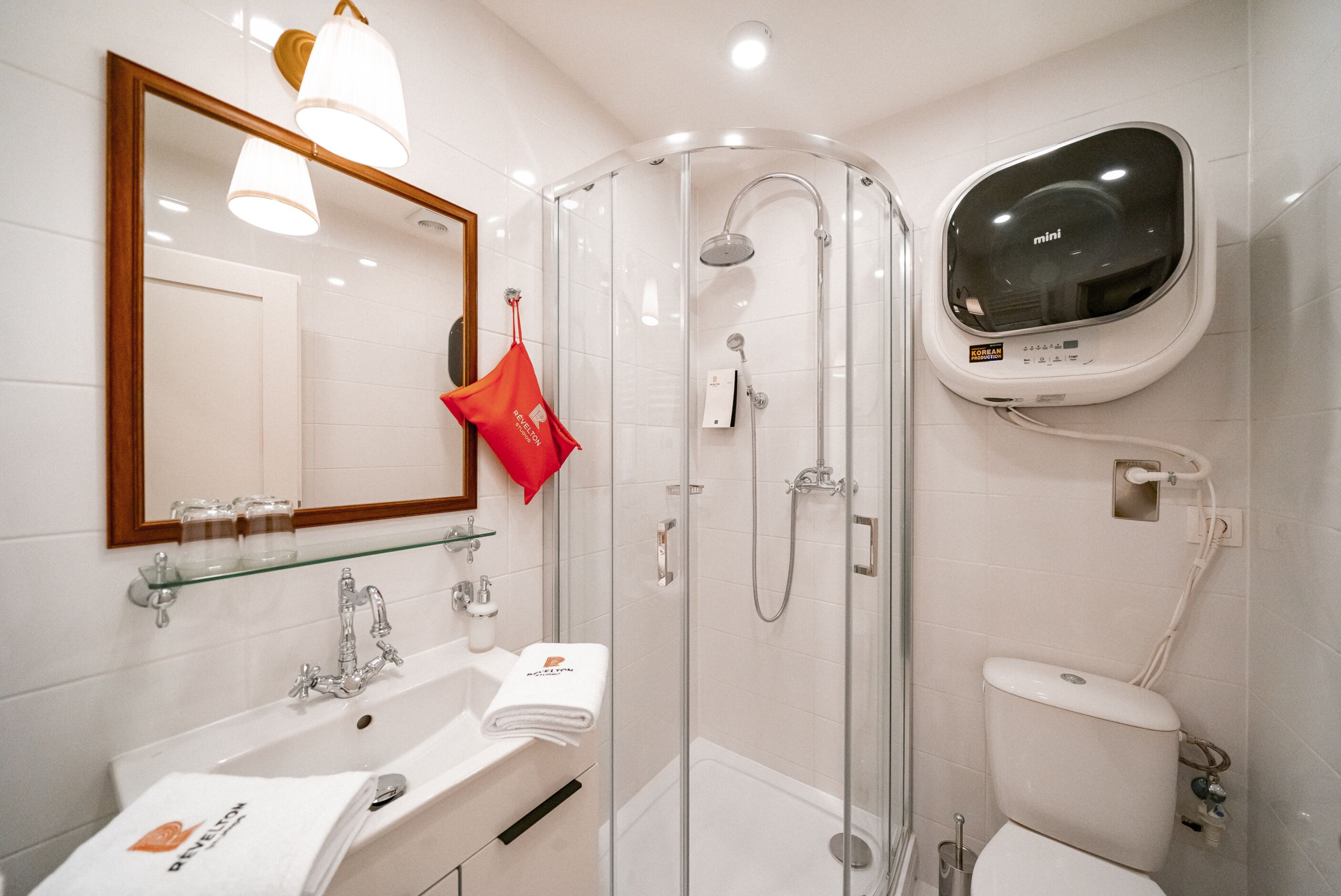Un bagno moderno con doccia vetrata, un lavandino bianco con ripiano in vetro e un water con bidet integrato.