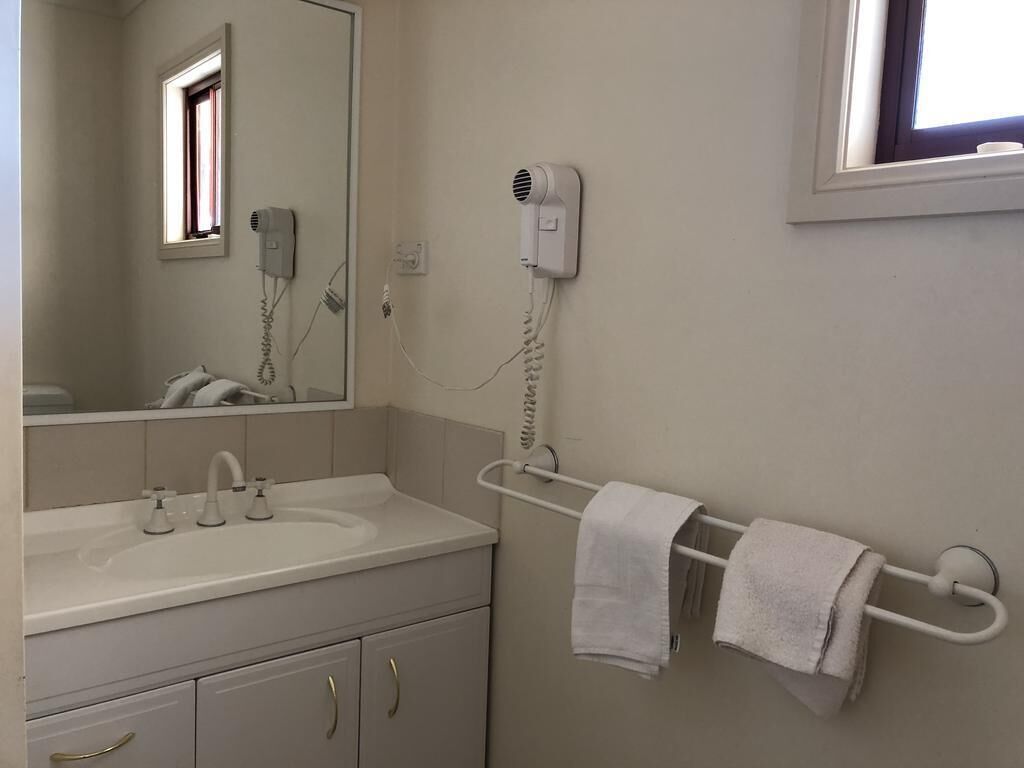A bathroom with a sink, mirror, towel rack, and a hairdryer on the wall.