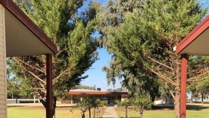 A pathway leading to a building with a red roof, surrounded by trees and a grassy area. - Outback Quarters Motel Hay and Restaurant (Hay South)