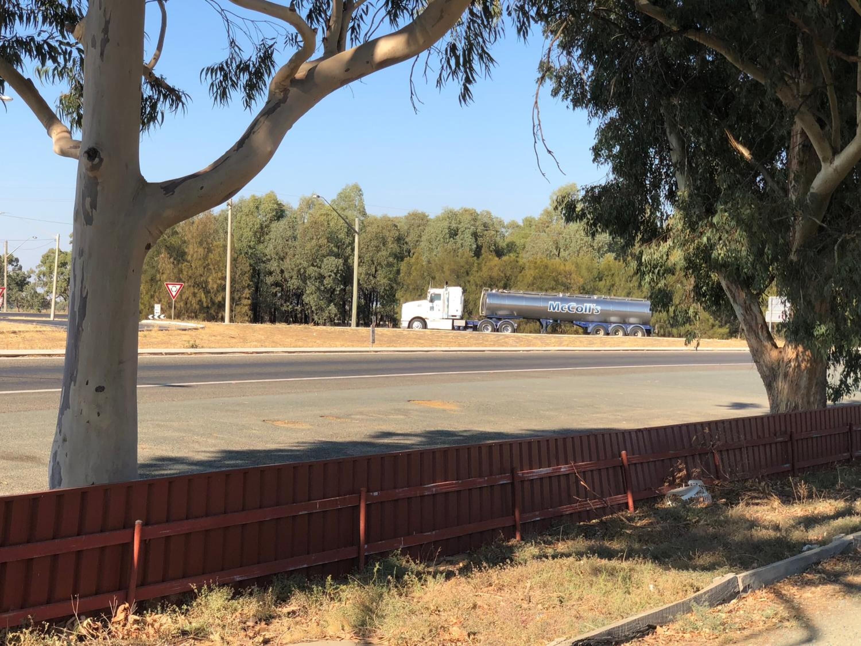 A road with a white truck and a tanker truck in the distance.