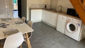 Una cocina compacta con lavadora, una mesa de comedor con sillas y una escalera.