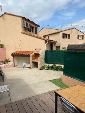 Un espacio al aire libre con una parrilla, una mesa y una silla.