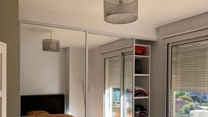 Een slaapkamer met een spiegelkast, een bed met een gestreept dekbed en uitzicht op de omgeving via een schuifdeur.