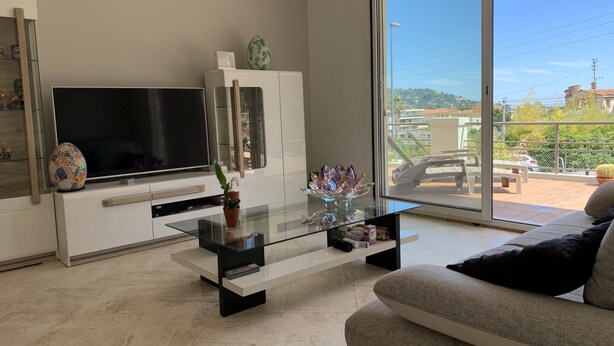 Een moderne woonkamer met een flatscreen televisie, een glazen salontafel en een bank.