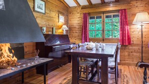 A cozy cabin interior with a wooden interior, a fireplace, a dining table, and a window with curtains. - Sunny 2-bedroom chalet in Megève, near slopes (Megève)