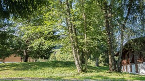 A grassy area with trees and a wooden structure. - Sunny 2-bedroom chalet in Megève, near slopes (Megève)