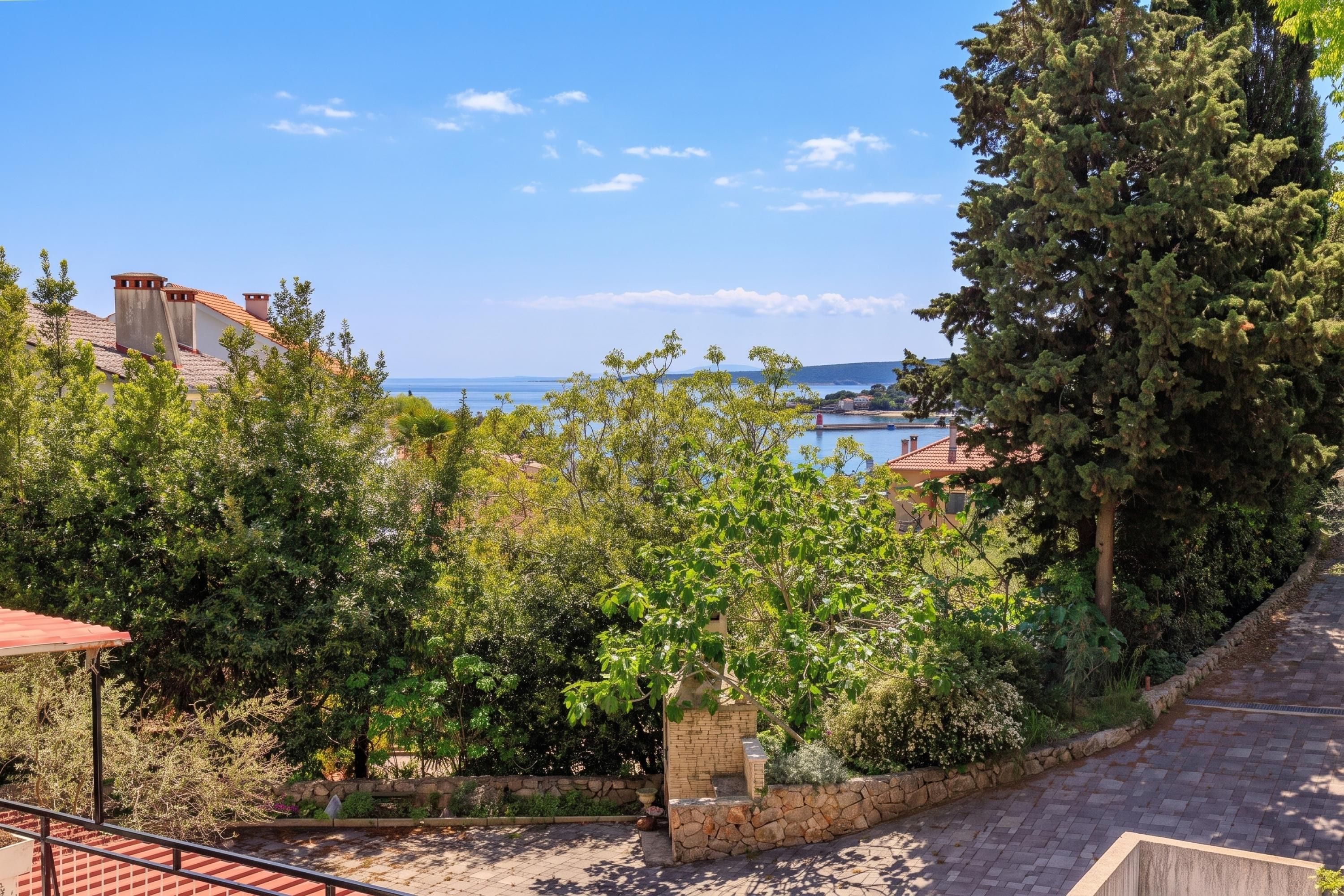 A coastal property with a stone pathway leading to a terrace overlooking the sea.