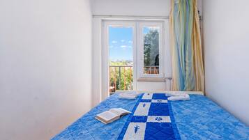 Un dormitorio pequeño con cama, ventana y vistas al exterior.