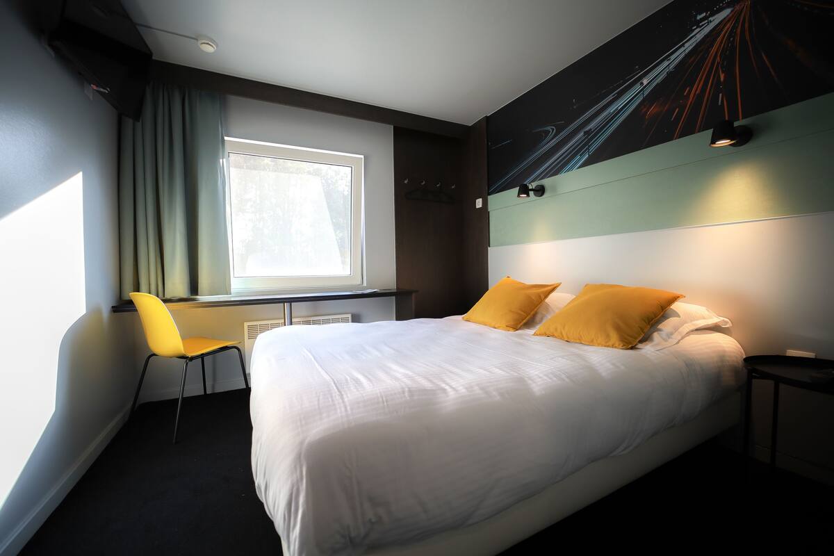 Moderni hotellihuone, jossa on suuri sänky, työpöytä ja tuoli.