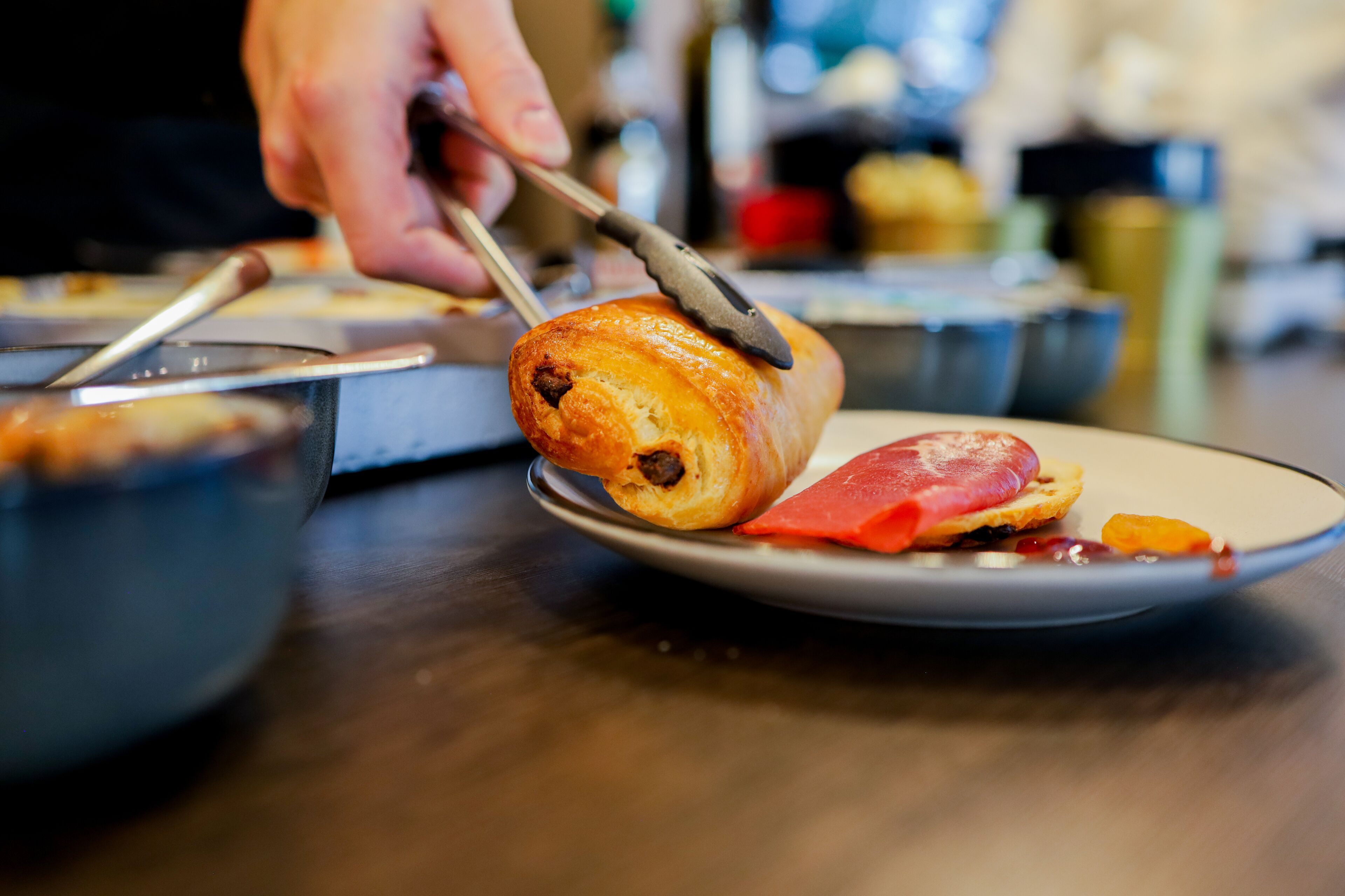 Une personne qui coupe une pâtisserie sur une assiette à l’aide d’un couteau.