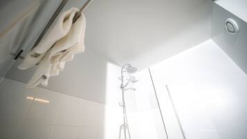 Ein modernes Badezimmer mit Glasdusche, Handtuchhalter und einem sichtbaren Oberlicht.