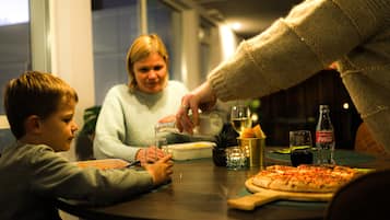 A dining table with a pizza, a bottle of Coca-Cola, and a glass of wine.