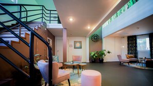 Un interior moderno con una escalera, zona de estar y un reloj grande en la pared.