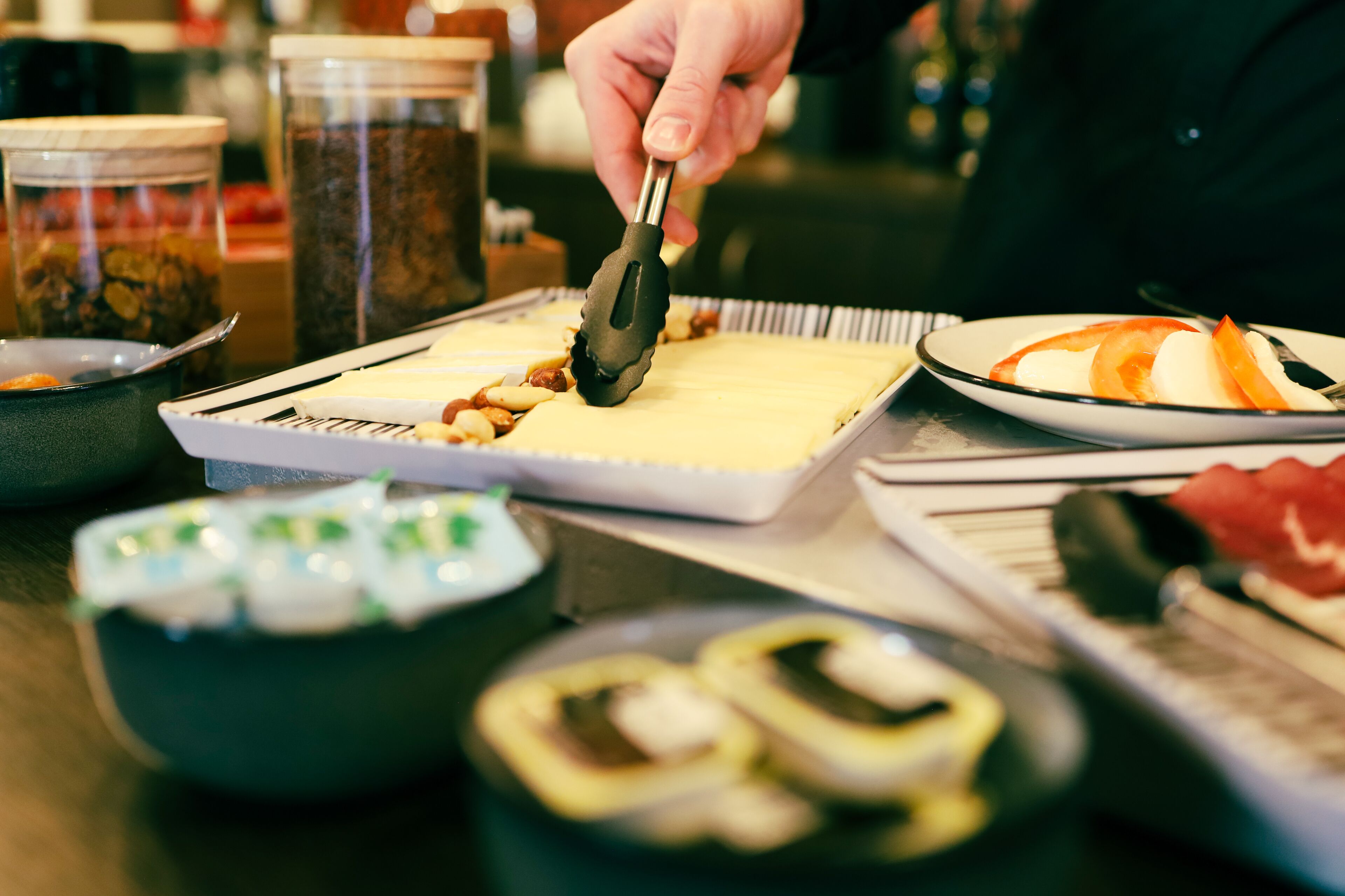 A person using tongs to place food on a tray.