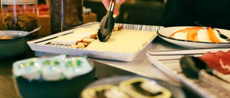 A person using tongs to place food on a tray.