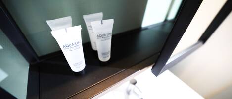 Un baño con espejo, lavabo y dos tubos de Aqua Line sobre la encimera.