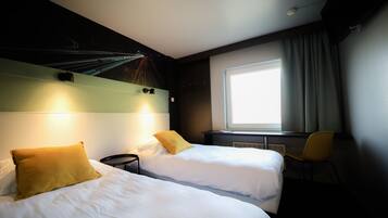 A hotel room with two beds, a window with curtains, a chair, and a wall with a light fixture.