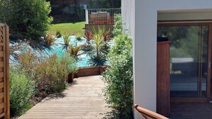 A wooden deck leading to a pool area with a view of a forested area.