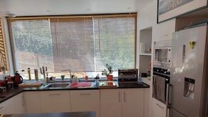 A modern kitchen with a large window, built-in oven, and stainless steel refrigerator.