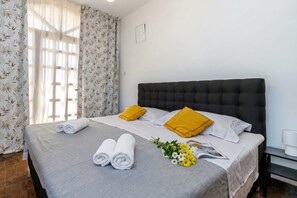 Un lit bien fait, avec des serviettes pliées, deux oreillers, un magazine et un petit bouquet de fleurs.