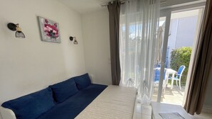 A room with a white sofa, a small white table, and a window with sheer curtains.