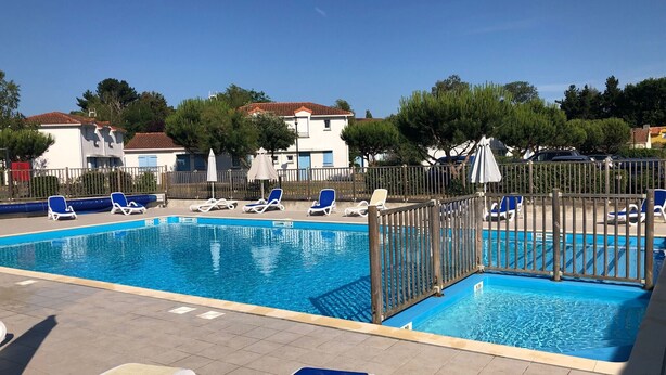A rectangular swimming pool with blue water, surrounded by lounge chairs and umbrellas.