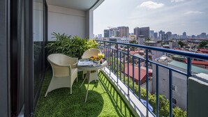 Un balcone con una porta vetrata, un tavolino con sedie e vista sulla città.