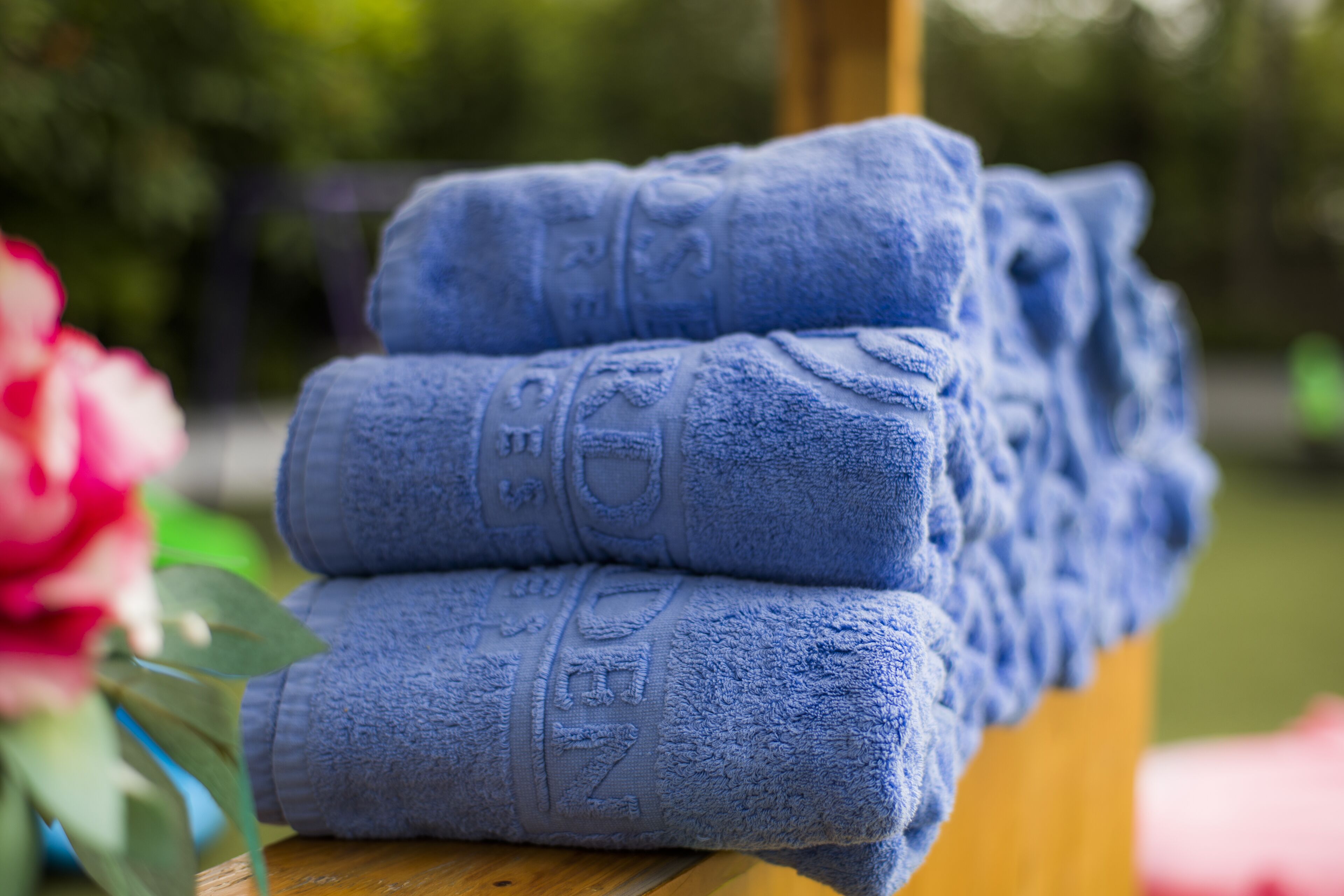 A stack of folded towels with embossed text, placed on a wooden surface.