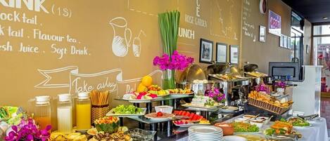 Een buffetopstelling met diverse gerechten en een drankstation, inclusief vruchtensappen en frisdranken.