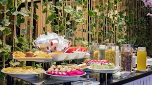Un buffet con diversi cibi e bevande, con sullo sfondo decorazioni di piante pensili.