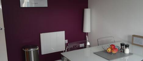 Una habitación moderna con una mesa blanca, paredes moradas, un mapa en la pared y un cubo de basura.