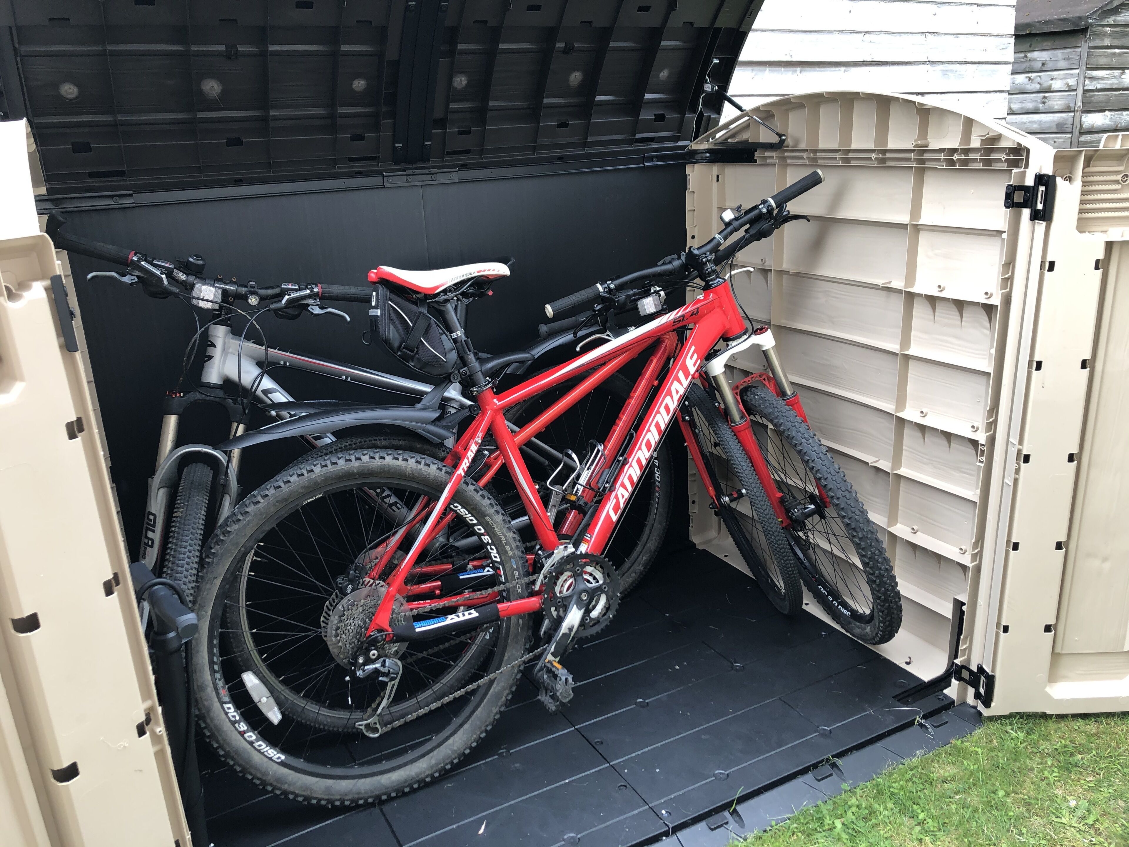 A red mountain bike parked inside a garage with a black floor and beige walls.