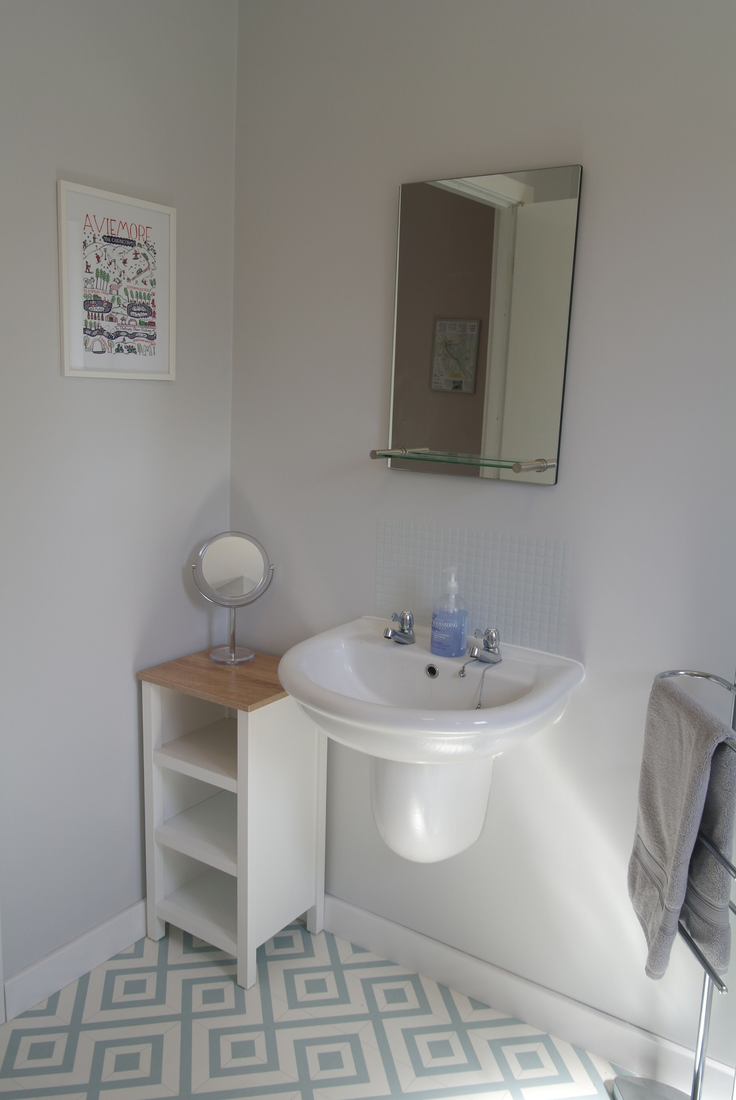 A bathroom with a white sink, a mirror, and a towel rack.