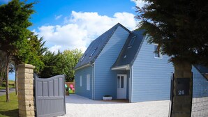 Een gelijkvloers huis met een grijze deur, een klein portaal en een grindpad.