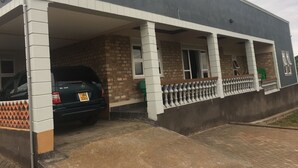 Um edifício de dois andares com varanda coberta e um carro estacionado na frente.