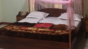 Uma cama com dossel, um edredom floral e uma mesa de cabeceira com abajur.