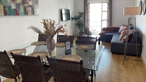 A modern living room with a glass dining table, wicker chairs, a grey sofa, and a floor lamp. - Malaga Center Flat Cathedral Balcony City Views (Málaga)