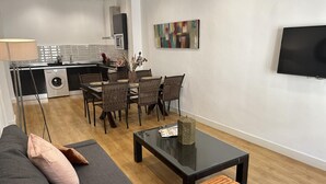 A modern living room with a sofa, coffee table, and dining area with chairs. - Malaga Center Flat Cathedral Balcony City Views (Málaga)
