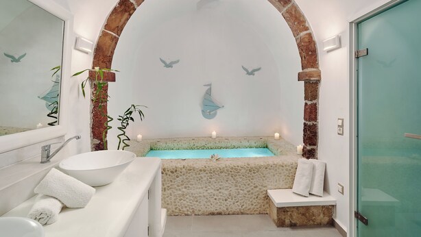 A bathroom with a stone bathtub, a white sink, and a large mirror.