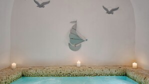 A spa area with a stone-lined pool, candles, and wall-mounted bird sculptures.
