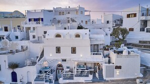 A white building with a pool, outdoor seating, and a staircase.