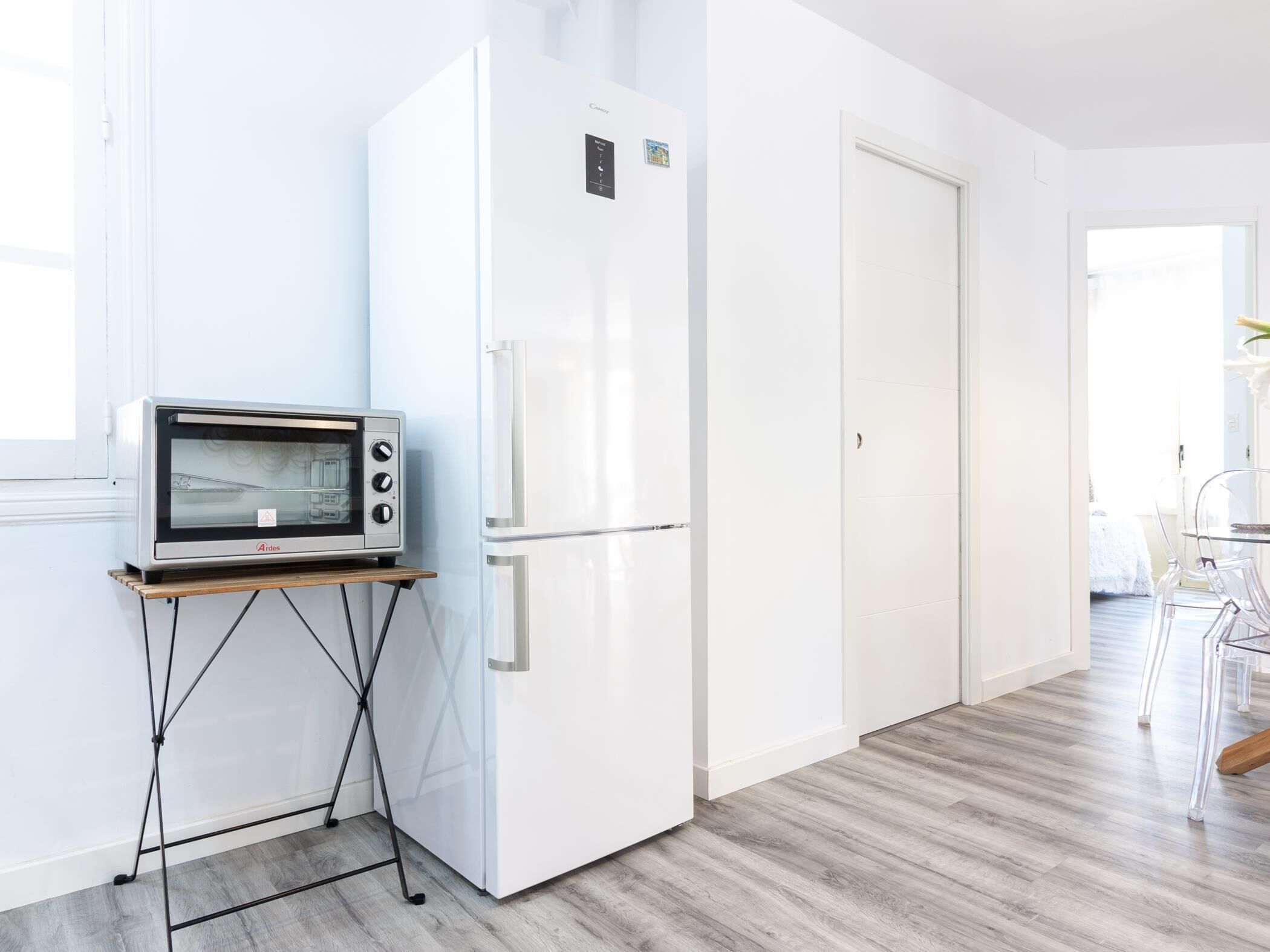 Une cuisine moderne équipée d’un four à micro-ondes encastré, d’un réfrigérateur blanc et d’une table à manger en bois avec des chaises.