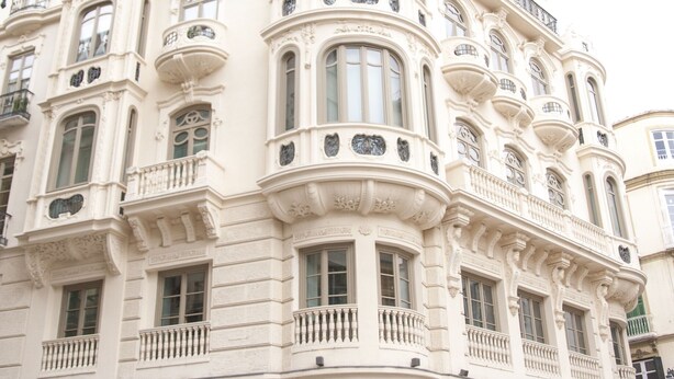 Ein historisches Gebäude mit aufwendigen architektonischen Details, darunter mehrere Balkone und dekorative Stuckarbeiten.