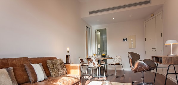 A modern living room with a leather sofa, a wooden coffee table, and a dining area with chairs and a table.