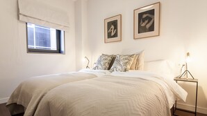 A double bed with a large window and two framed pictures on the wall. - Malaga Luxury City Center. Parking (Málaga)
